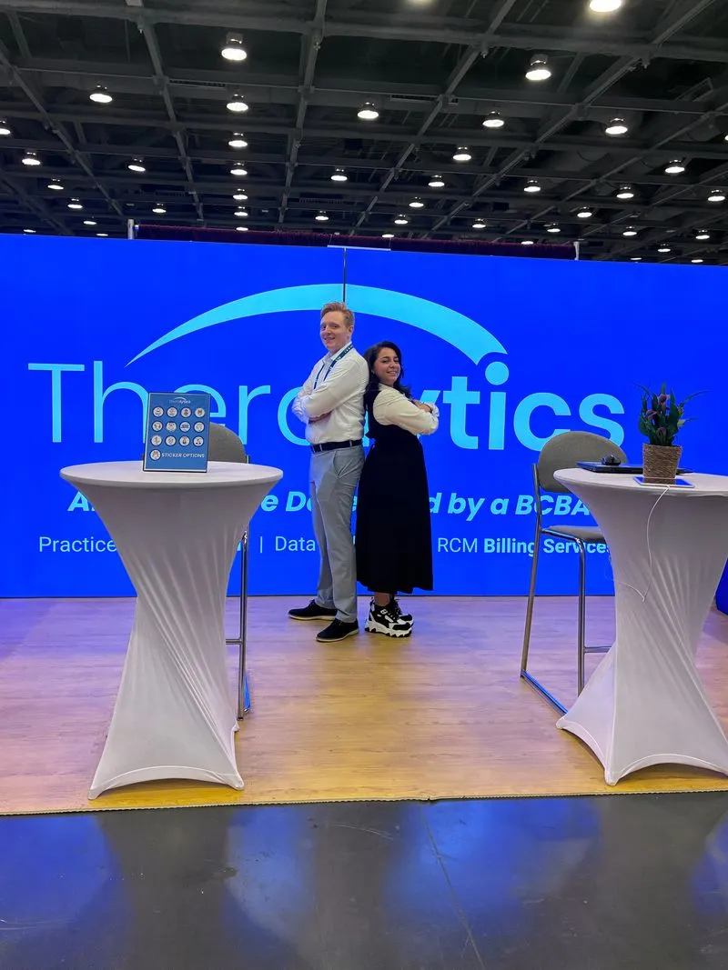 Two Theralytics team members welcoming visitors at an ABA conference booth